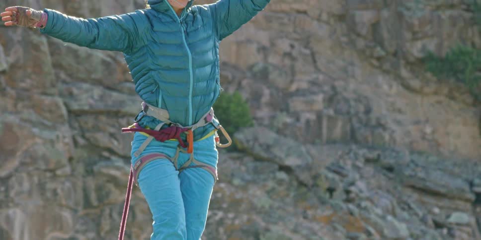 A woman is tight rope walking over a mountain range