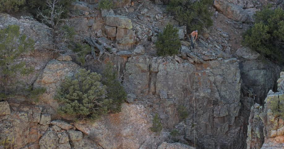 Aerial view of a man pulling rope on the side of a cliff