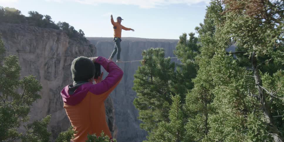 A man walks on a tightrope over a canyon