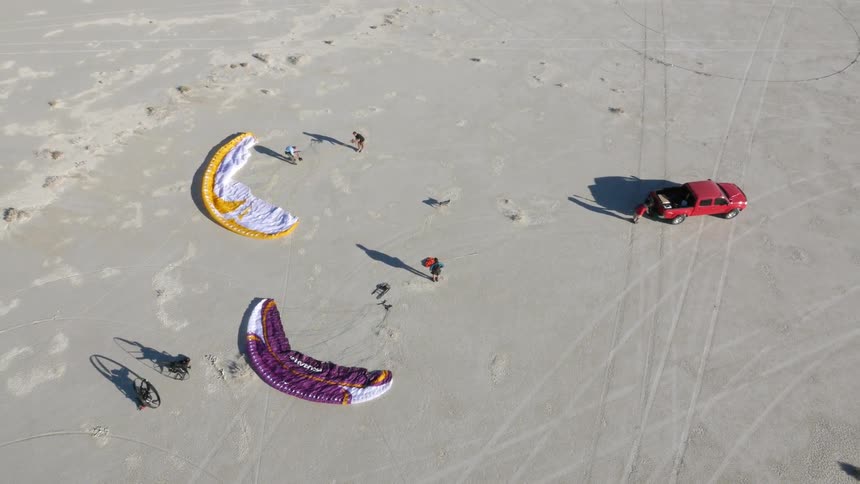 Aerial view of people preparing their equipment for parasailing using fans to propel them