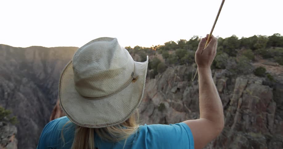 Woman touching a rope that is suspended above a deep canyon