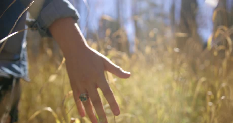A woman is walking through a grassland area during the day