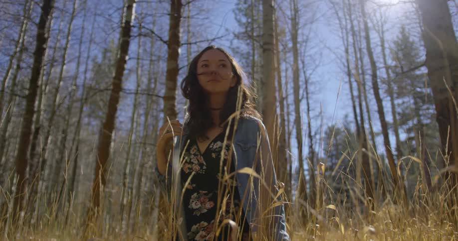 A woman is walking through a grassland area