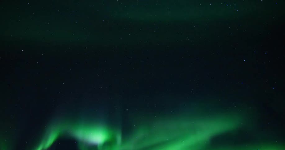 Time lapse of green waving aurora polar northern lights in the sky at night