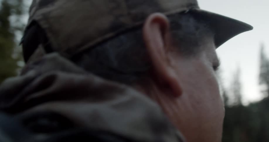 Man wearing a hat hikes through the pine forest