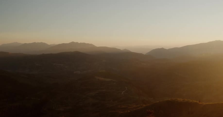 Mountain range in a hazy sky with sun flare