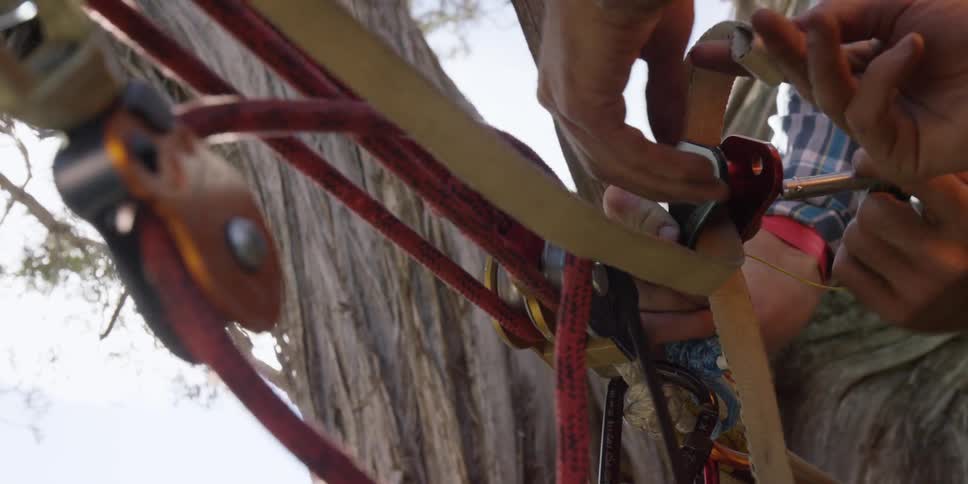 Two people are fastening rope to buckles