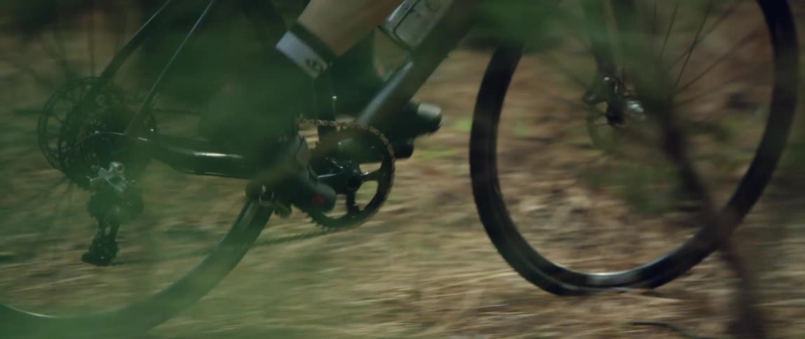 medium side tracking shot of a bicycle riding on a forest path