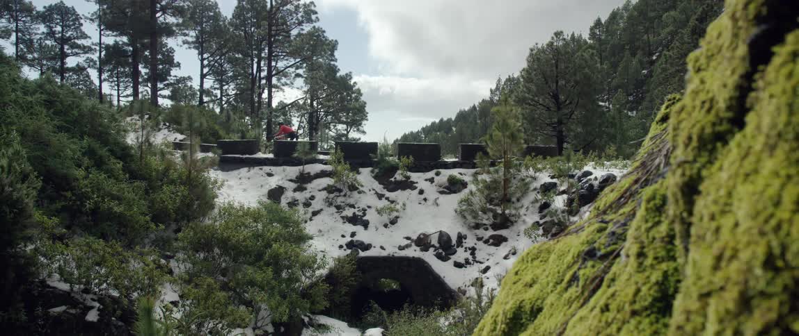 wide dolly shot of Cyclist riding over a bridge through a snow covered landscape