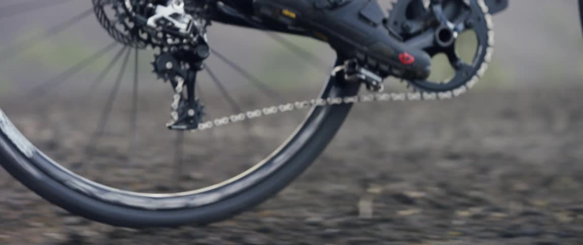 close up of the chain transmission on a bicycle in motion on a gravel road