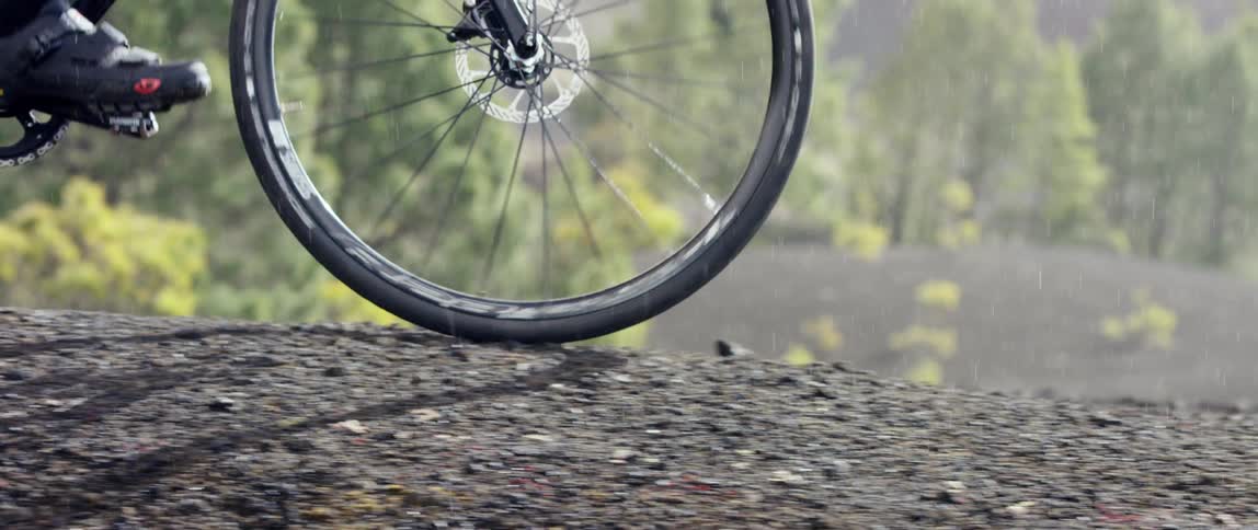 gravel bike riding on the top of a slope on a dirt trail in the rain at daytime
