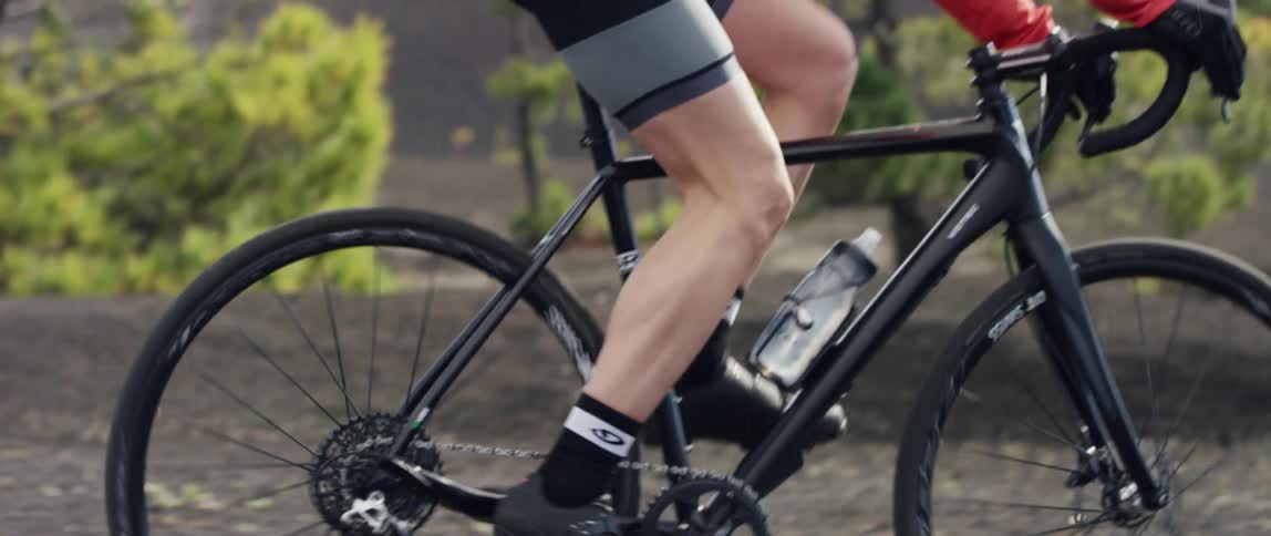 medium side shot of a cyclist pedaling over black gravel