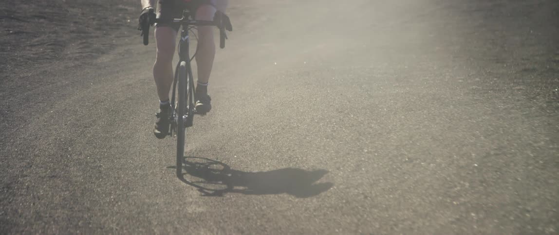 cyclist riding a bike on a dusty gravel road, breaking and throwing up gravel