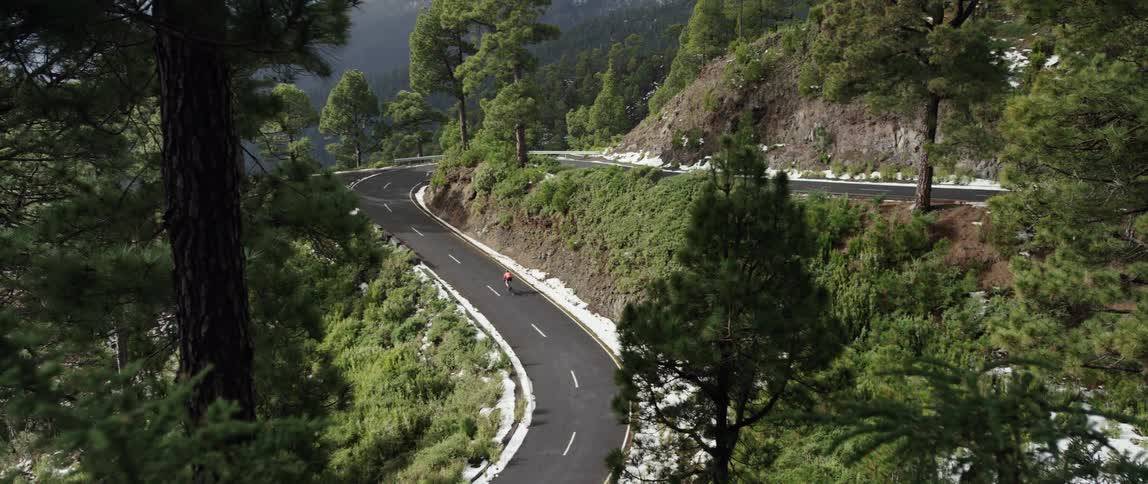 cyclist pedals a bicycle up a scenic forest mountain curved road