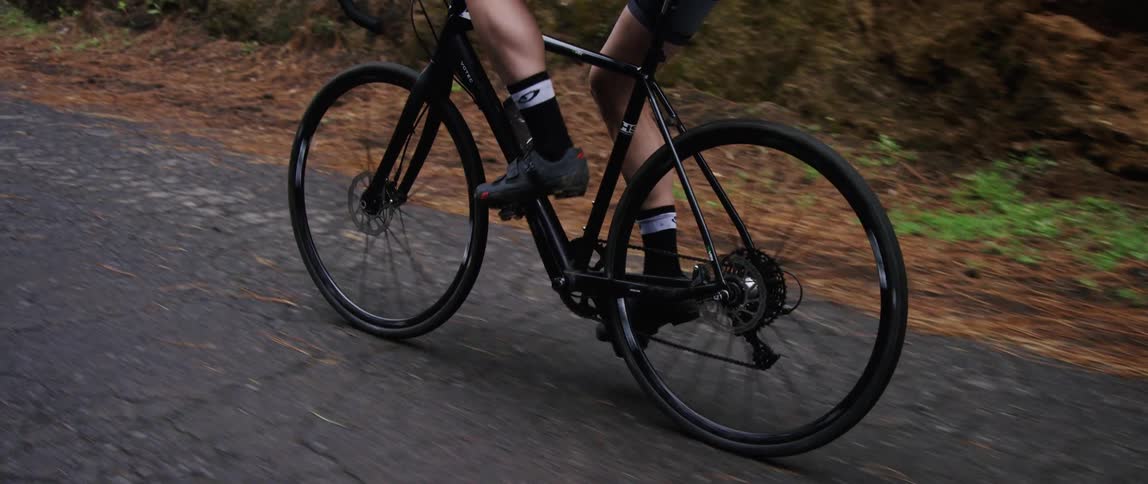 Muscular strong cyclist riding a bicycle on a gravel road outdoors