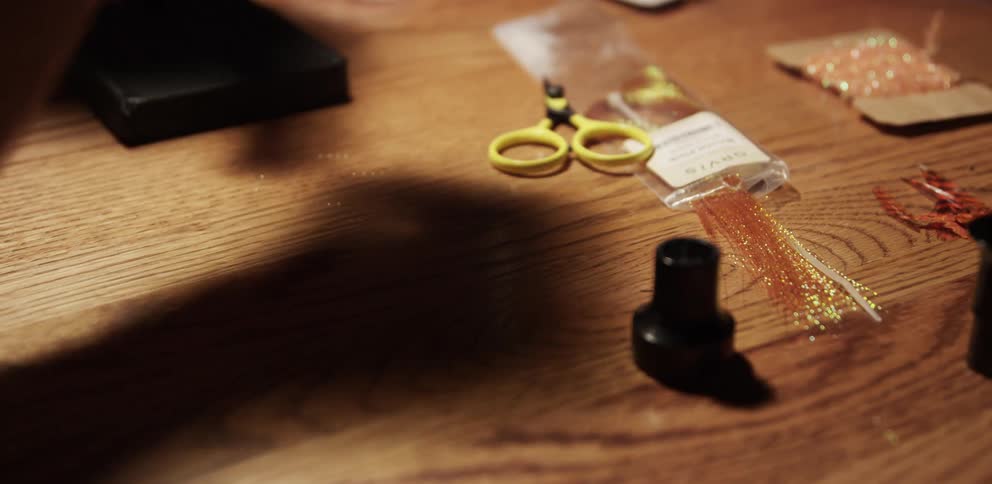 A man threads a needle and cuts the excess thread
