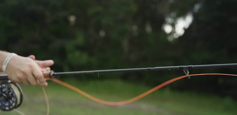 Persons hands cast a fishing line to catch fish from a lake