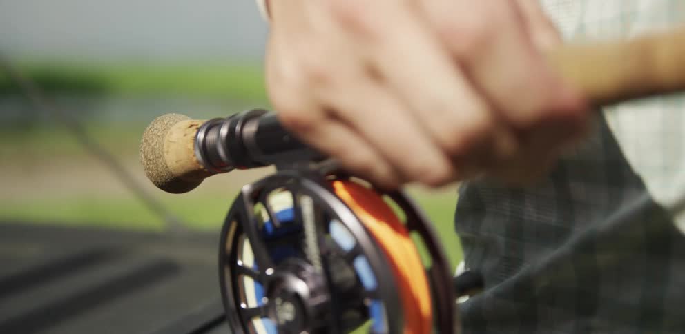 Man hanging a lure in the hook of a fishing rod outdoors