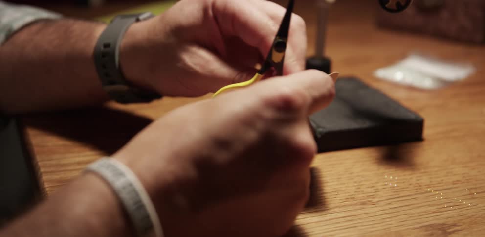 A man unwraps some thread and cuts a piece off