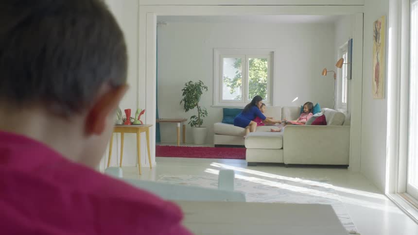 A woman sits on the couch with her children