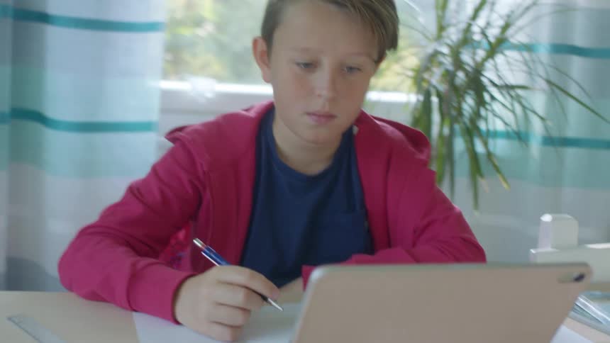 Young boy take remote classes on a tablet at home