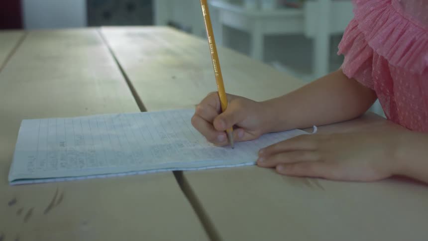 Child is writing on a paper with a pencil