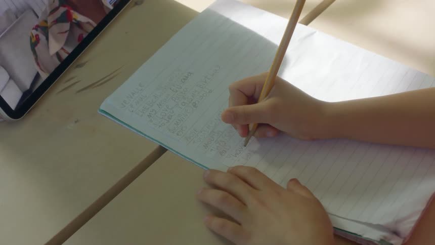Girl sitting at the table doing homework with pen and paper at home
