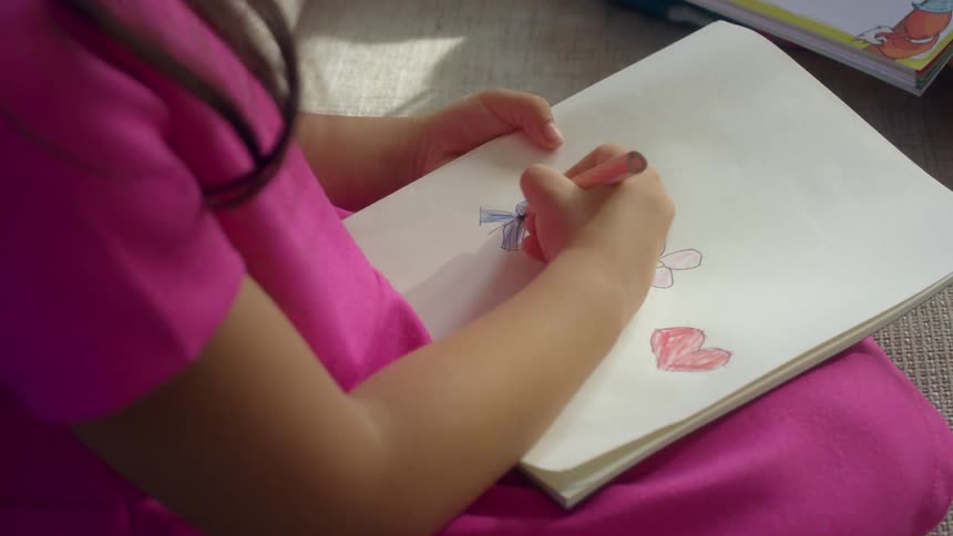 Sitting girl draws on sketchpad in her lap