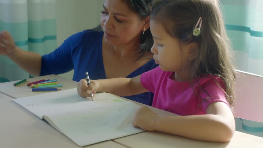 A woman helps her daughter choose a crayon to use while coloring