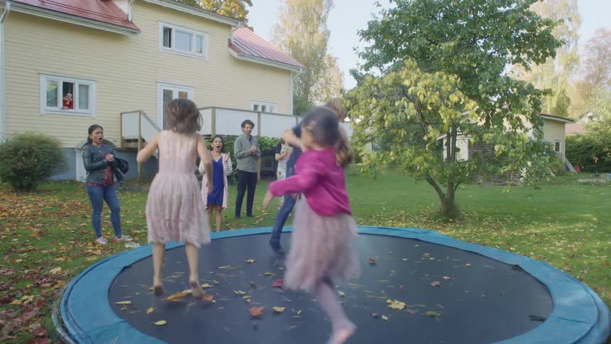Kids jumping on trampoline in backyard while parents watch
