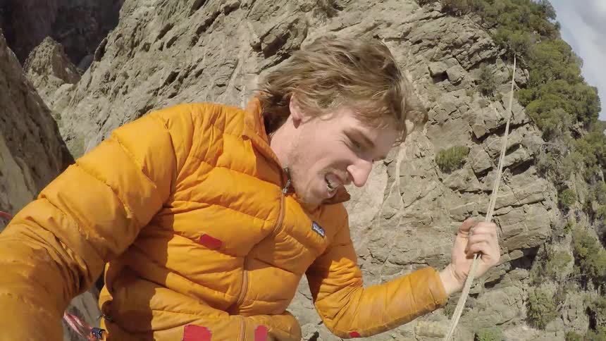 A man grabs a rope over a canyon