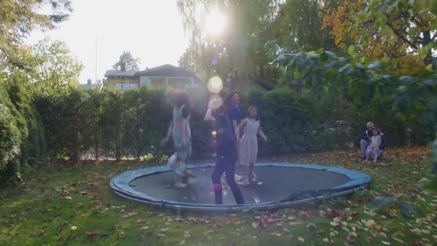 A group of children jump together on a backyard trampoline