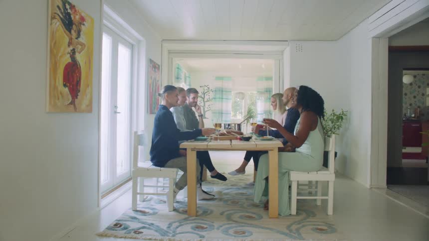 A group of people sit together at a home dinner table