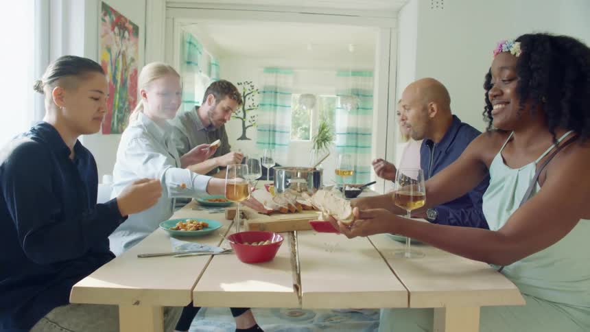 A group of people sit at a home dinner table eating food