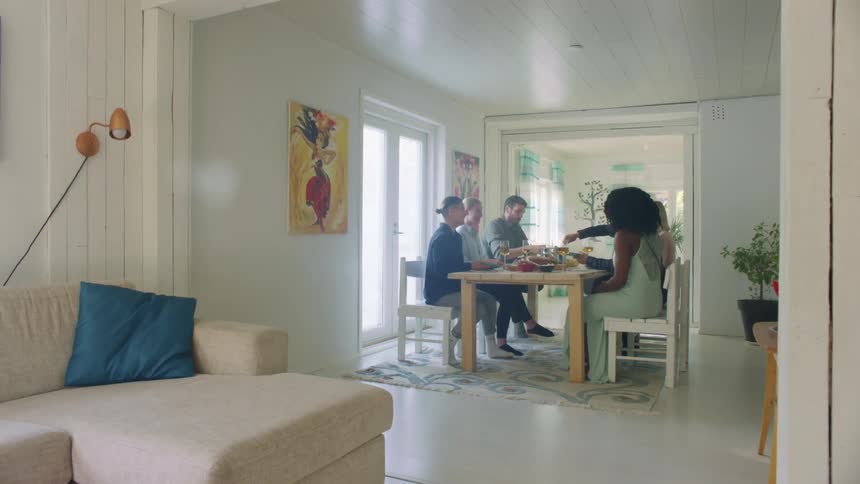 A group of people sit at a home dinner table together