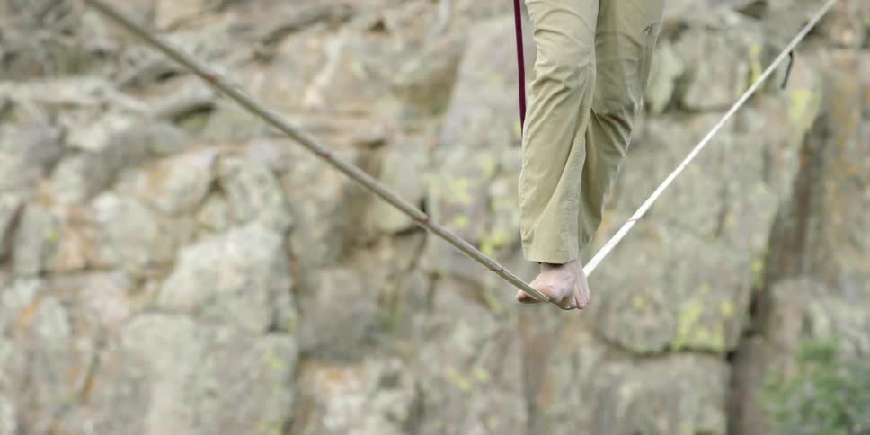 Man balances on a rope strung up in a canyon