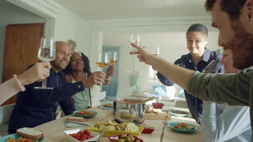 Friends and family toasting with wine over lunch at home