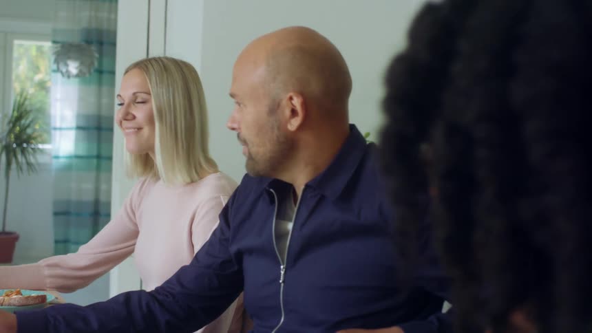 A man sits and talks with two women at a table in a home