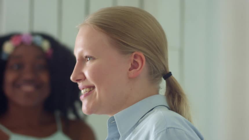 Young women laugh and talk in pale walled room