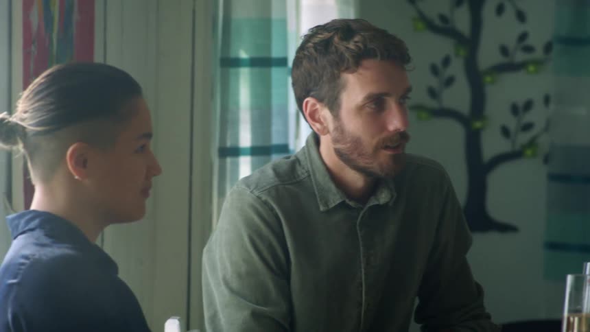 A man and a woman sitting at a table in a room with a window in the background