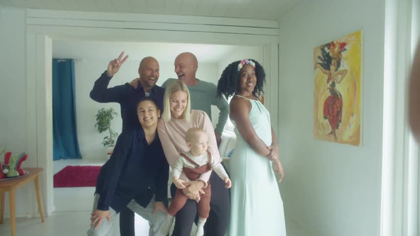 A group of people stand close together posing for a man taking their picture