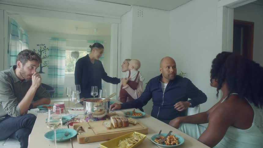 A group of people sit around a table at home and talk