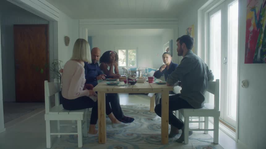 Friends and family talking over lunch at the dining table at home