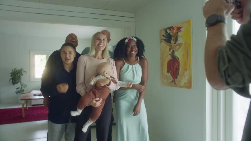 A few men women and a baby gather for a photo standing in a home