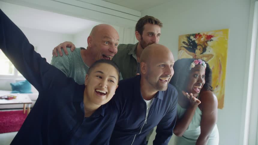 A small group of men and women pose for a picture inside in front of a living room