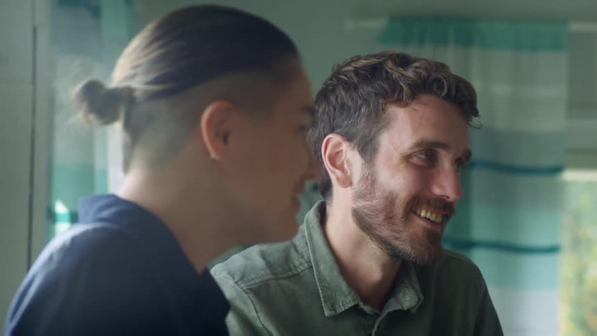 A man and woman are sitting at a table talking and laughing