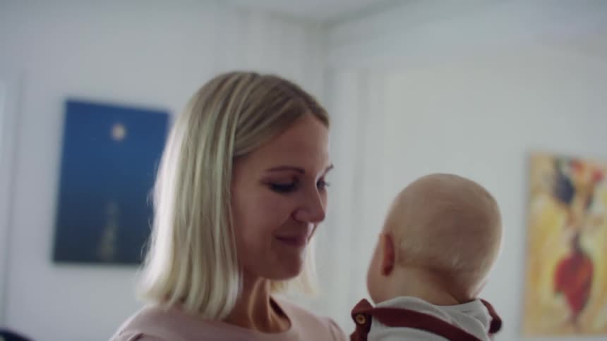 A woman playfully shakes a baby in the air before cradling him