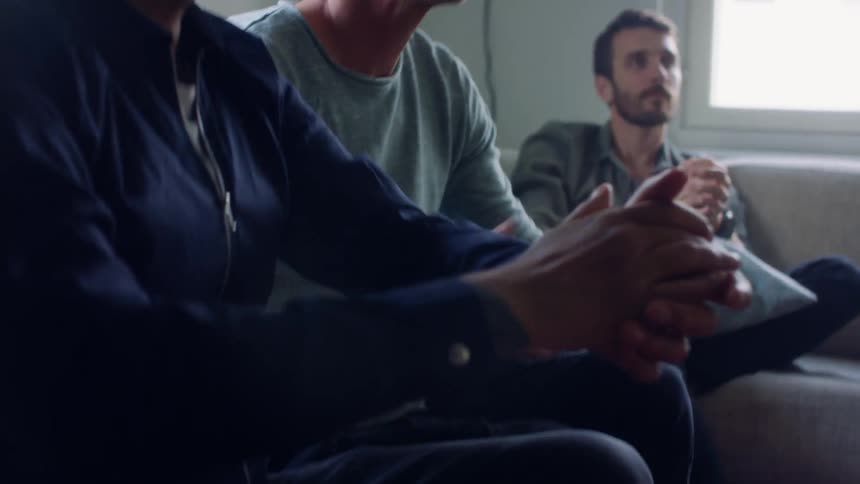 A group of men sit together clapping their hands