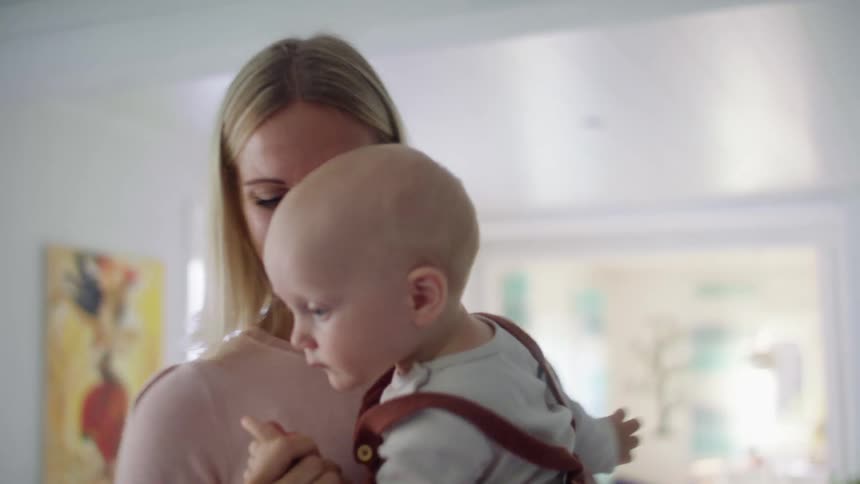 A mother holds an infant baby and dances in circles