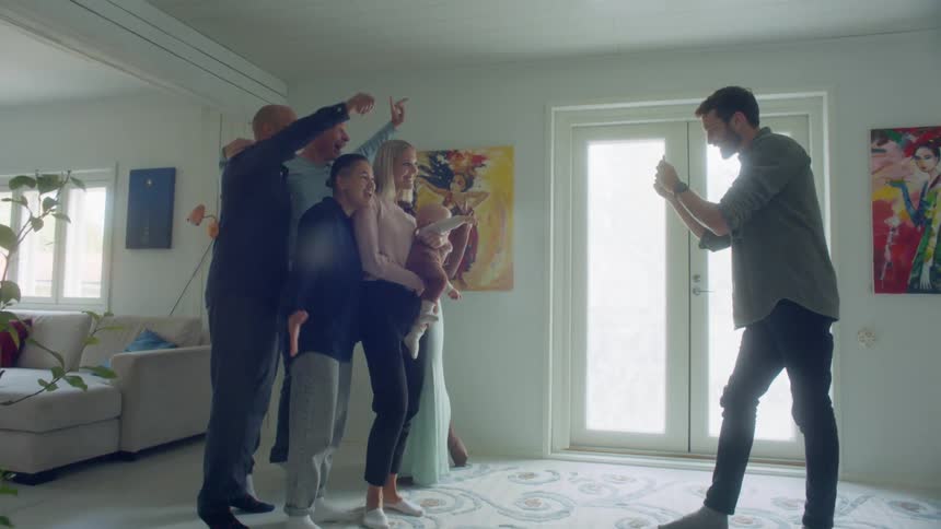 A group of men women and a baby pose for another man taking a photo of them